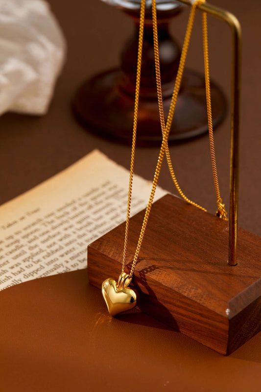 Golden heart pendant necklace by SUIHE Jewelry displayed elegantly on wooden stand.