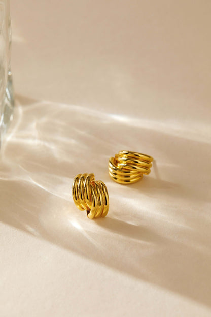 Gold-plated Wave Earrings by SUIHE Jewelry featuring sculptural curves and elegant design on a light background.