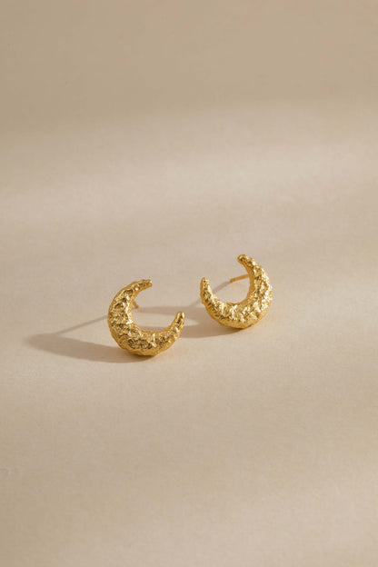 Gold-plated textured crescent moon earrings by SUIHE Jewelry on a beige background.