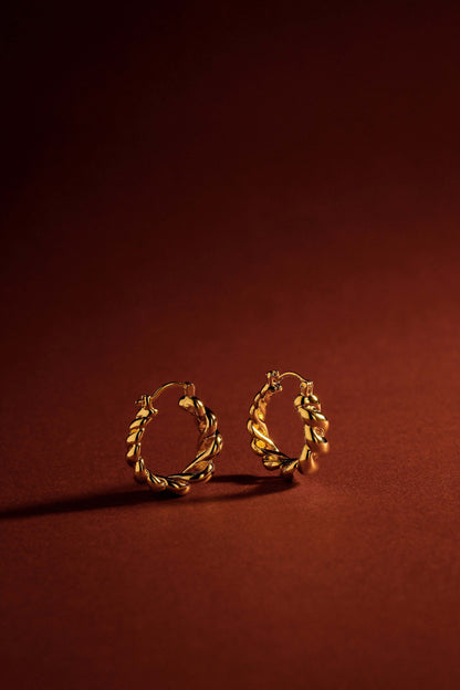 Twisted Hoop Earrings in 18k Gold Filled over Copper on a deep orange background, by SUIHE Jewelry, showcasing elegance and modern style.