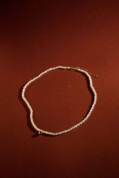 Celestia freshwater pearl necklace by SUIHE Jewelry featuring 18k gold vermeil chain, with pearls on a rich brown background.