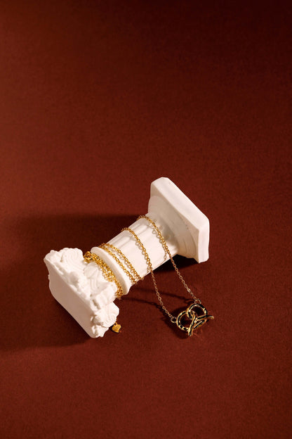 SUIHE Jewelry 'Pretzel' Necklace in 18k Gold Vermeil, displayed elegantly on a classic white pedestal against a warm background.