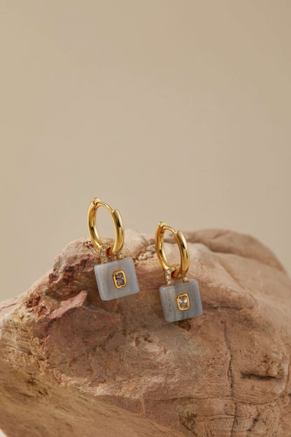 Gold-plated huggie hoops with aquamarine lock pendants and zircon accents by SUIHE Jewelry, symbolizing clarity and inner peace.
