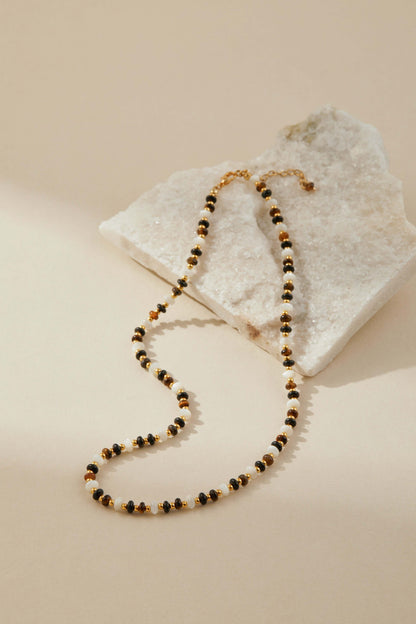 SUIHE Jewelry Marble Necklace with marbled beads, pearls, and gold-tone accents on a stone surface, elegant and versatile design.