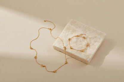 18k gold vermeil SUIHE Jewelry croissant mini charm necklace on beige background.