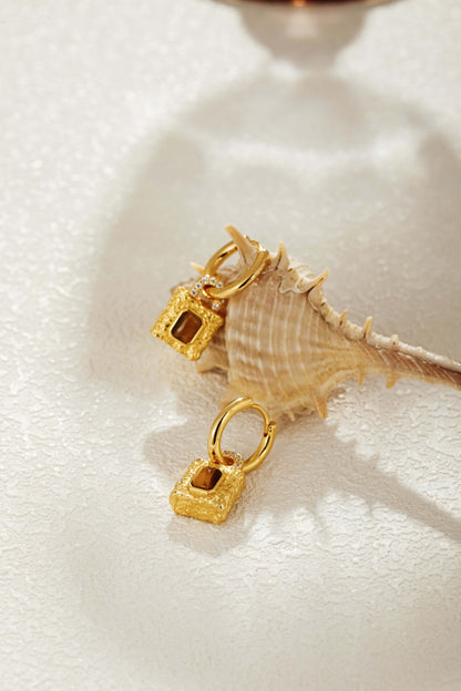 Gold-plated huggie hoop earrings with Tiger Eye stone lock pendants by SUIHE Jewelry, showcasing resilience and sophistication.