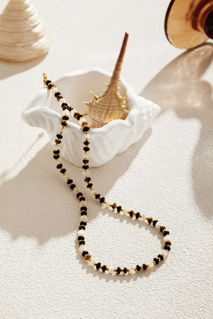 Gold and black beaded necklace displayed in a white seashell bowl, showcasing SUIHE Jewelry's elegant and modern design.