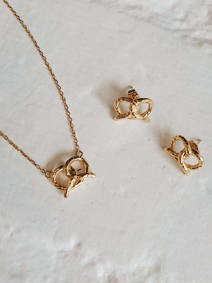 18k Gold Vermeil Pretzel Stud Earrings and Necklace by SUIHE Jewelry on a textured surface