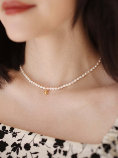 Woman wearing Celestia Freshwater Pearl Necklace by SUIHE Jewelry, featuring 3-4mm pearls and 18k gold vermeil pendant, close-up view.