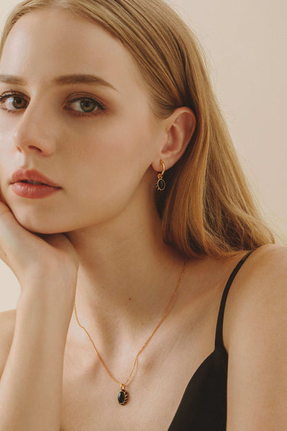 Woman wearing Eclipse Black Onyx and Enamel Necklace by SUIHE Jewelry, featuring a gold vermeil chain, paired with matching earrings.