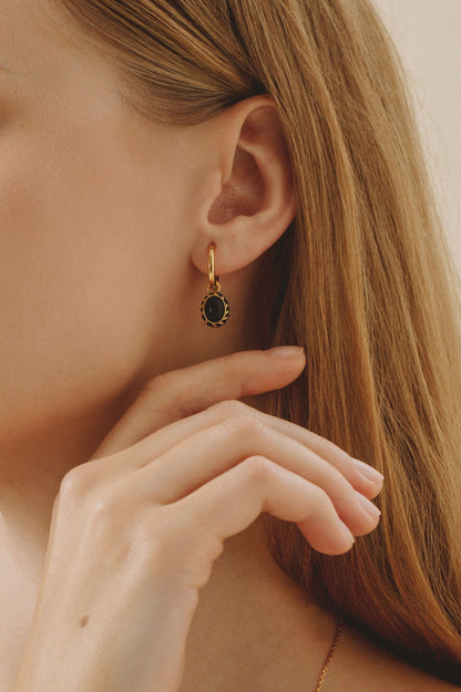 Eclipse black onyx and enamel gold-plated earrings by SUIHE Jewelry on model's ear.