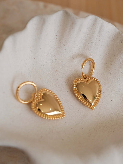 SUIHE Jewelry Adore Heart Charm Hoop Earrings with gold-tone pendants and beaded detailing on a white dish.