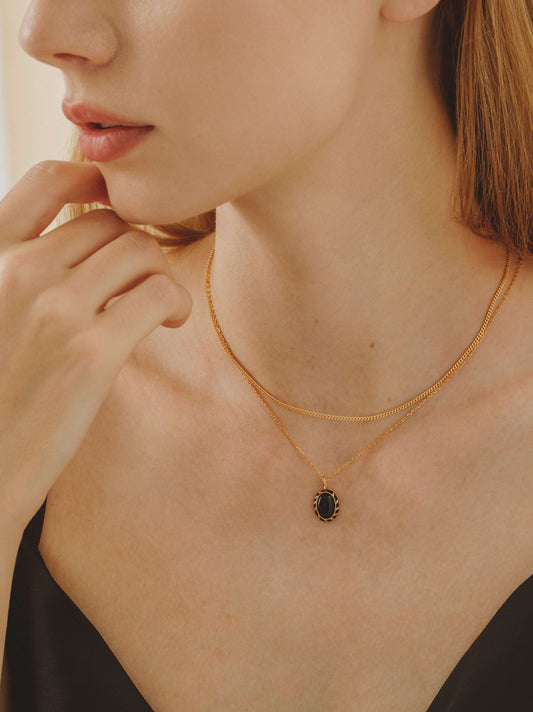 Woman wearing SUIHE Jewelry's ‘Eclipse’ necklace featuring black onyx and enamel pendant on a gold chain.