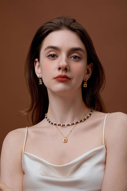 Woman wearing SUIHE Jewelry Lock Tiger Eye Stone Necklace with gold lock pendant and earrings, exuding elegance and confidence.