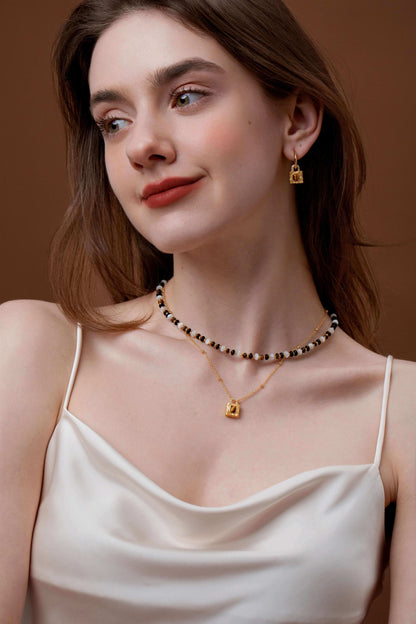 Woman wearing SUIHE Jewelry Tiger Eye Stone Necklace with gold lock pendant and matching earrings.
