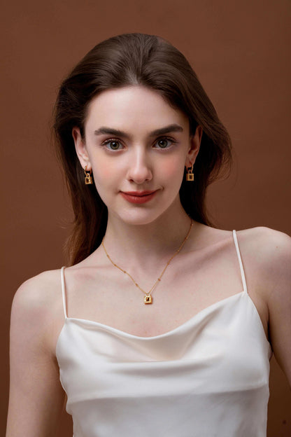 Woman wearing SUIHE Jewelry Lock Tiger Eye Stone Necklace with gold lock pendant and matching earrings.