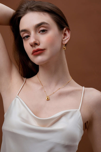 Woman wearing Lock Tiger Eye Stone Necklace by SUIHE Jewelry with a textured lock pendant and gold-plated chain in elegant setting.
