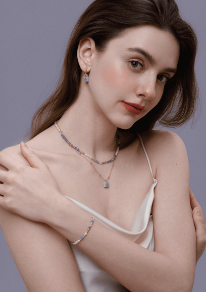 Woman wearing Ocean Natural Gemstone Bracelet by SUIHE Jewelry, featuring blue, lavender, and white gemstones and gold-plated beads.