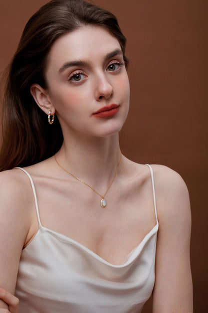 Woman wearing SUIHE Jewelry Dough Twist Hoop Earrings and necklace, elegant style with a white top against a brown background.