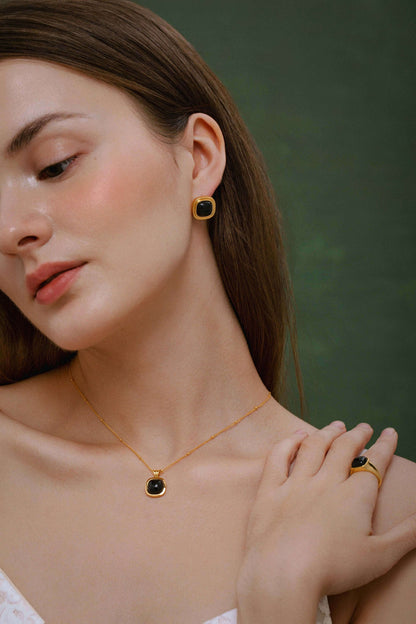 Model wearing SUIHE Jewelry "Nocturne" Black Onyx Square Necklace with matching earrings and ring against a green background.