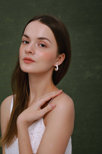 Woman wearing Luna white enamel hoop earrings by SUIHE Jewelry, highlighting lunar elegance and sophistication.