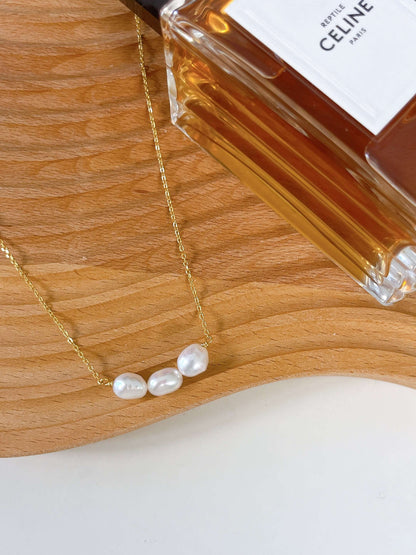 "Baroque Tears" freshwater baroque pearl necklace on 18k gold vermeil chain by SUIHE Jewelry next to a perfume bottle.
