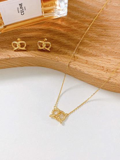 SUIHE Jewelry "Pretzel" Necklace in 18k Gold Vermeil with matching earrings on a wooden surface.