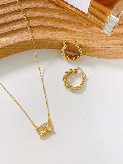 SUIHE Jewelry Pretzel Necklace in 18k Gold Vermeil with sculptural design, inspired by Parisian brunches, on wooden background